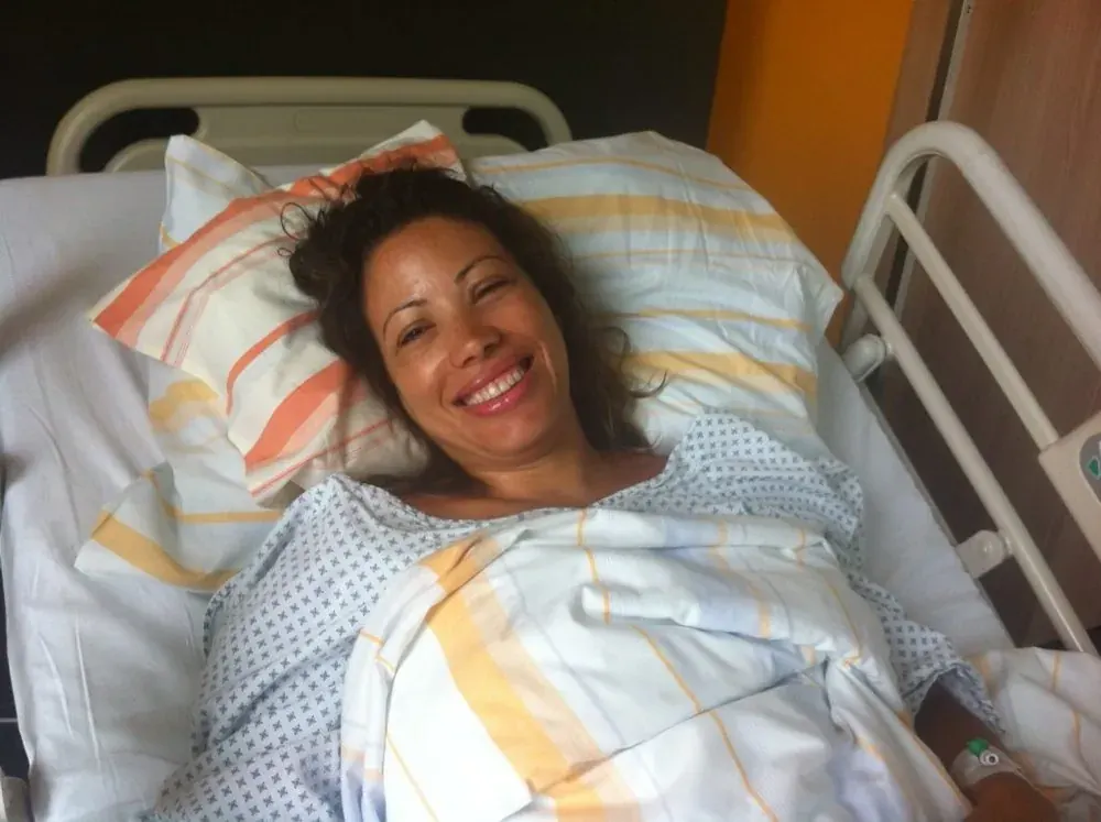 Patrícia em 2014, internada, sorrindo na cama do hospital