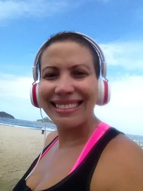 Patrícia na praia, de fones, com o cabelo começando a crescer