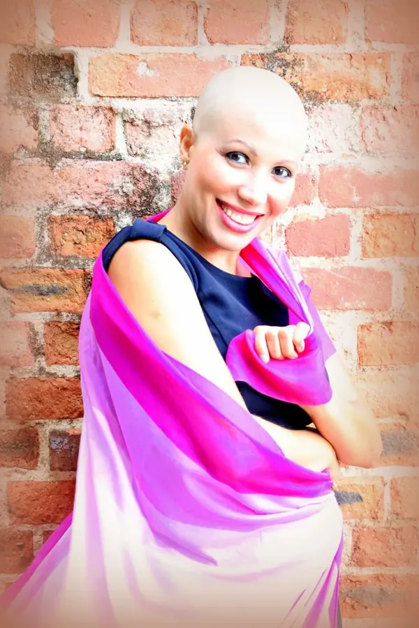 Patrícia careca durante a quimioterapia, sorrindo, com o lenço rosa