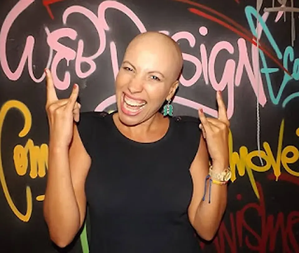 Patrícia careca, sorrindo e fazendo pose descontraída